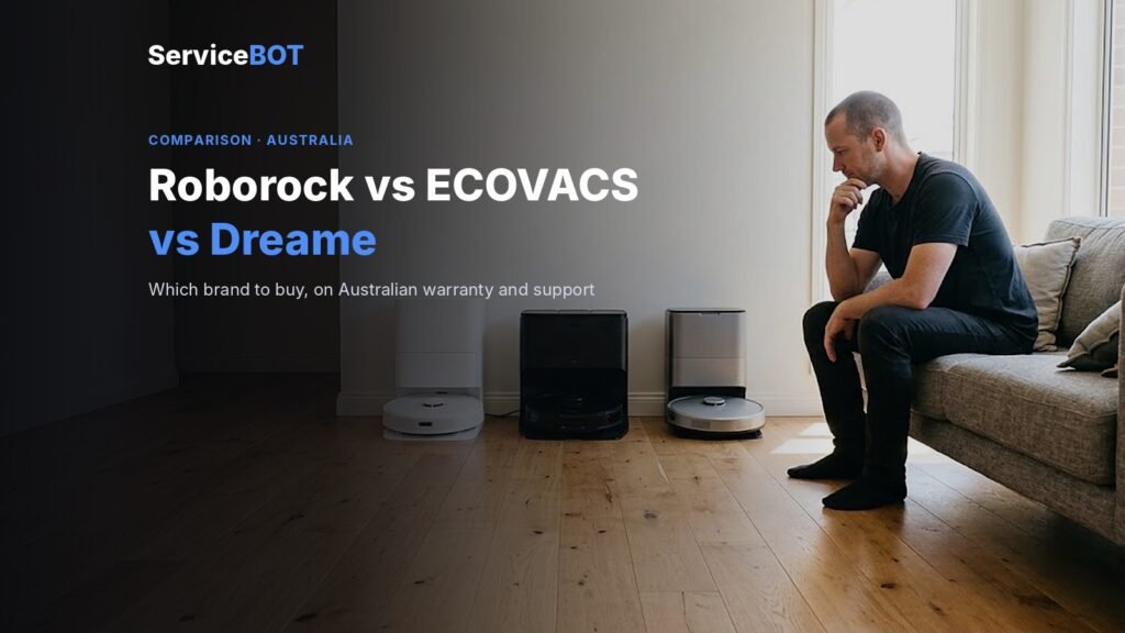 A man sits on the edge of a couch, chin in hand, weighing up three unbranded robot vacuums in white, black and silver lined up in front of their docks on timber floorboards