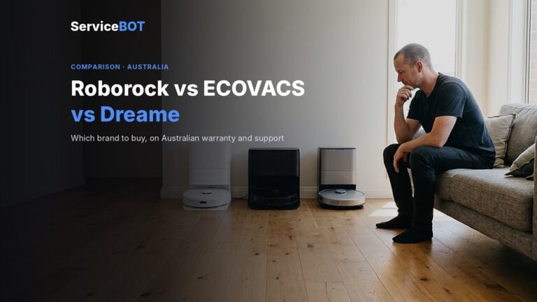 A man sits on the edge of a couch, chin in hand, weighing up three unbranded robot vacuums in white, black and silver lined up in front of their docks on timber floorboards
