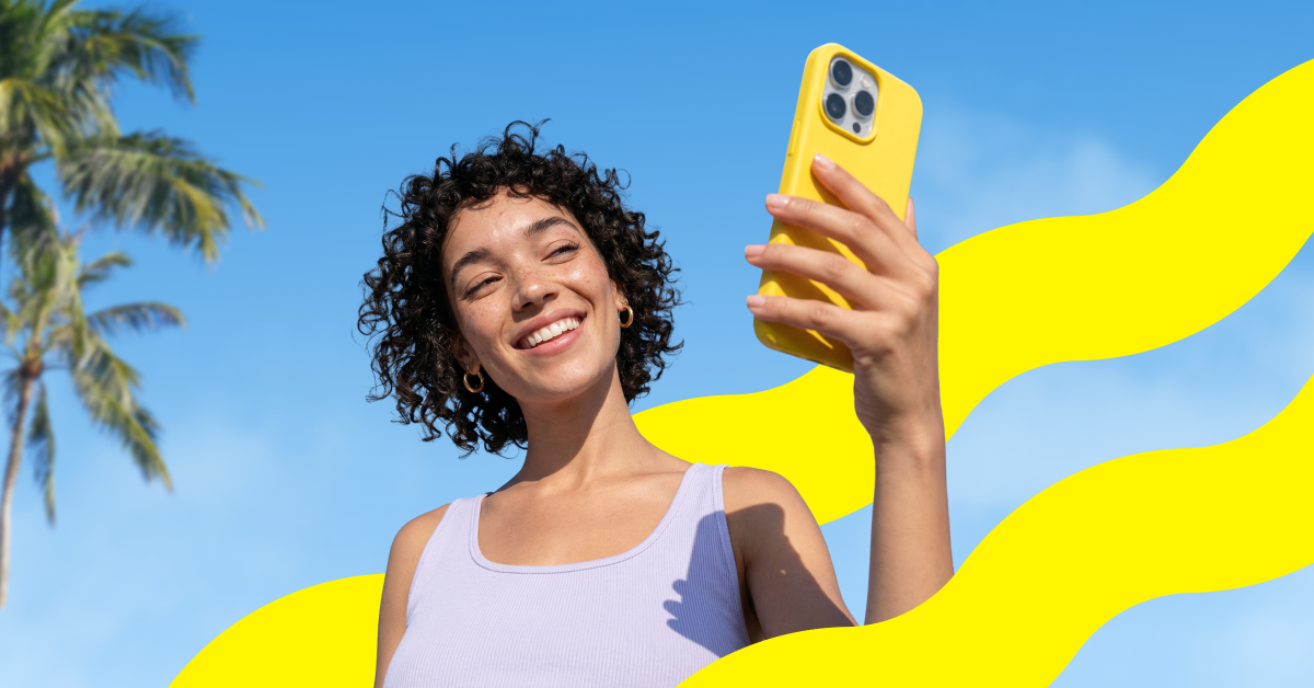 A woman outdoors smiling at her phone