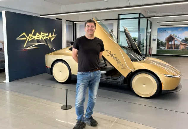 ServiceBot founder Ed standing beside a gold Cybercab in a showroom, its door raised